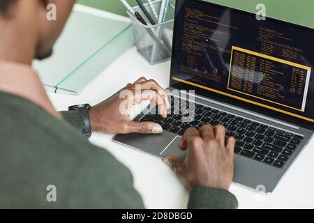 Rear view of developer typing on laptop developing the software he working at workplace at office Stock Photo