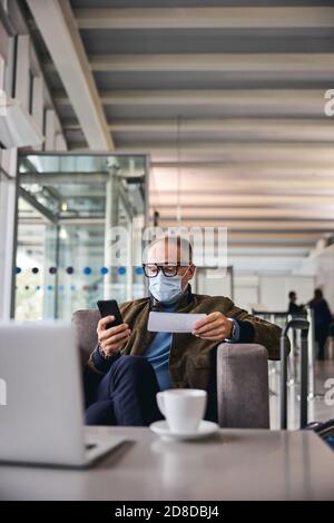 Concentrated man in a mask gazing at his smartphone Stock Photo