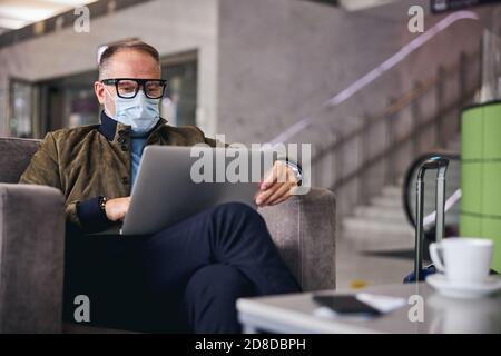 Male traveler working on the laptop in the lounge area Stock Photo