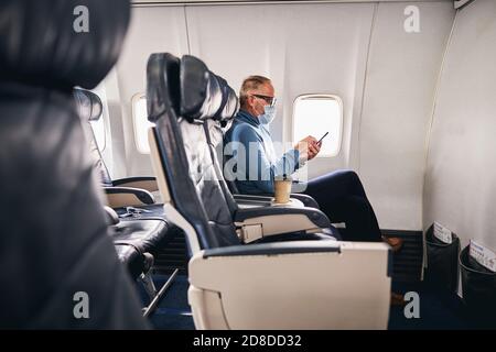 Concentrated businessman using his cellphone during the flight Stock Photo
