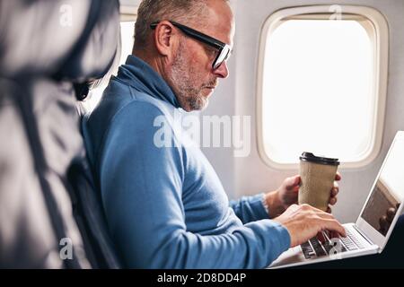 Airline passenger using his computer for work Stock Photo