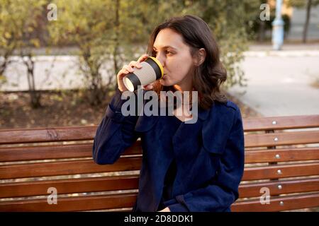 Beautiful woman with dark hair drinking coffee outdoors Stock Photo