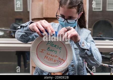 London, UK.  29 October 2020.  A woman takes part in a protest outside the Department for Education in Westminster by affixing paper plates with messages directed at the UK government to reconsider their recent decision not to provide free school meals until Easter 2021.   Footballer Marcus Rashford’s campaign to provide school meals continues to receive public and business support.  Credit: Stephen Chung / Alamy Live News Stock Photo