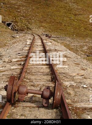 Rail tracks leading to the mouth of an abandoned mine in the Svalbard archipelago. Stock Photo