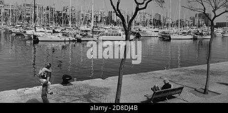A young couple embrace on the embankments of Marina Port Vell. Barcelona. Spain Stock Photo