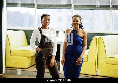 Two african woman in dress posing at restaurant. Stock Photo