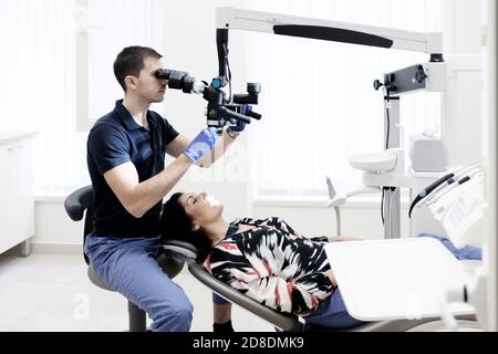 Dentist working on female patient ,using dental microscope Stock Photo