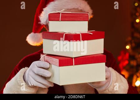Santa holding stack of gift boxes in front of his face he bringing them to holiday Stock Photo