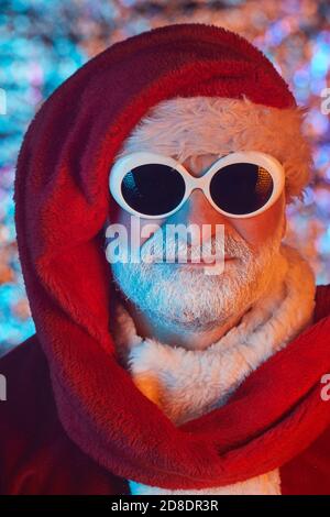Close-up of senior man dressed as a Santa wearing sunglasses and hat looking at camera Stock Photo