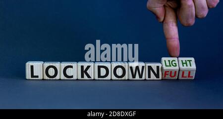 Symbol for a second lockdown. Hand turns cubes and changes the expression 'lockdown full' to 'lockdown light'. Copy space. Beautiful white background. Stock Photo