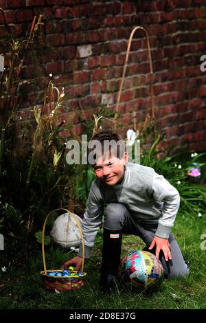 A young boy searching for Easter eggs in the garden. at home in Wales. On a warm March day a young boy goes on a Easter egg hunt on the 28th of March Stock Photo