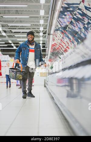 At the Supermarket: Full Length Vertical Shot of a Stylish African American Guy Dances Through Fresh Produce Section of the Store. Having Fun Shopping Stock Photo