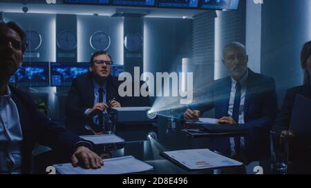 Government Officials, Military Men and Business Executives Watching Presentation in the Conference Room. Working Projector on the Table. Collaboration Stock Photo