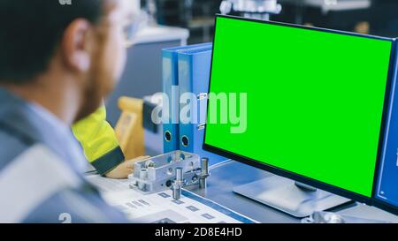 Close-up Back View of the Mechanical Engineer Working on Personal Computer with Green Screen Mock up GReat for Template. Professional Working At the Stock Photo