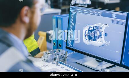 Close-up Back View of the Mechanical Engineer Designing 3D Engine Model on Personal Computer. Professional Working At the Factory. Stock Photo