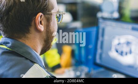 Close-up Back View of the Mechanical Engineer Designing 3D Engine Model on Personal Computer. Professional Working At the Factory. Stock Photo