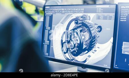 At the Factory: Female Mechanical Engineer Designs 3D Engine on Her Personal Computer while Male Automation Engineer Uses Laptop for Programming Stock Photo