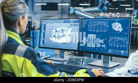 At the Factory: Female Mechanical Engineer Designs 3D Engine on Her Personal Computer, Male Automation Engineer Uses Laptop for Programming Robotic Stock Photo