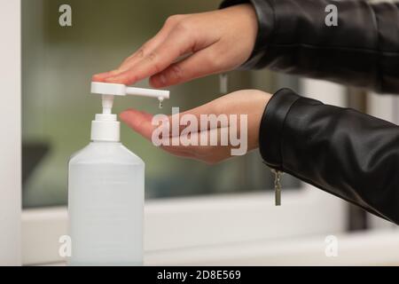 Female hand pressing bottle and pouring alcohol-based sanitize on hands. Disinfection concept. Liquid soap with pumping from bottle. Applying a Stock Photo
