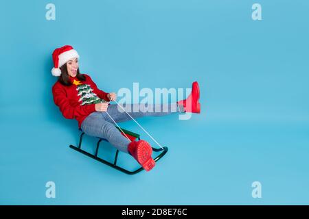 Photo portrait of woman riding sled screaming isolated on pastel light blue colored background Stock Photo