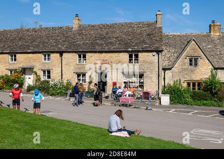 Cyclists and walkers outside the Old Post Office on the green in the Cotswolds, Guiting Power, England Stock Photo