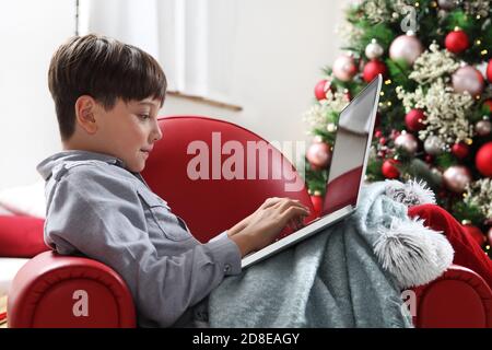 merry christmas, child at home with computer near the illuminated and decorated tree Stock Photo