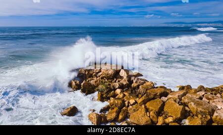 Aerial top view of Atlantic ocean big waves hitting on stone waterbreak 