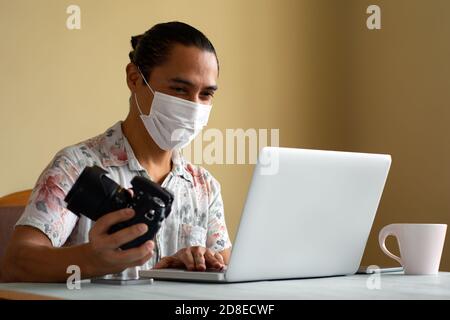 Latino photographer with medical mask works at home. Copy space. Coronavirus concept. Stock Photo