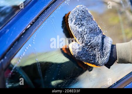 One person hand with microfiber mitten washes a vehicle window with water and soap Stock Photo