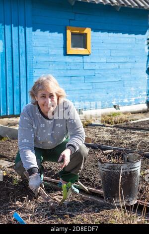 Senoir Caucasian woman weeds in her garden Stock Photo