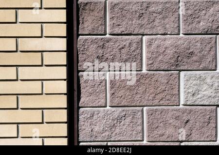 Wall with facing bricks. Different types of bricks on the facade of the fence. Yellow and gray bricks. Stone wall background. Stock Photo