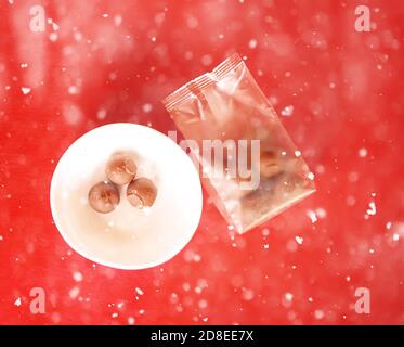 Sweet chocolate truffels on red background in snowfall. Stock Photo