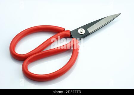 Tailor's scissors on a white background. Multi-purpose red scissors with large handles for trimming and sewing. Tailoring tools. Stock Photo
