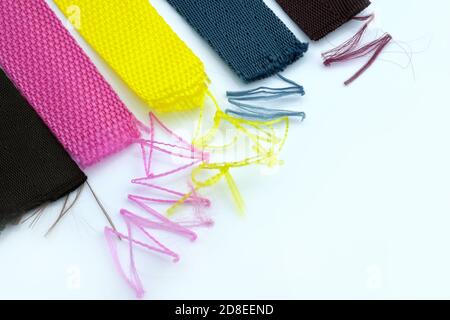 Multi-colored textile belts with threads sticking out on a white background. A strap tape that slips. The belt is unraveled with threads. Stock Photo