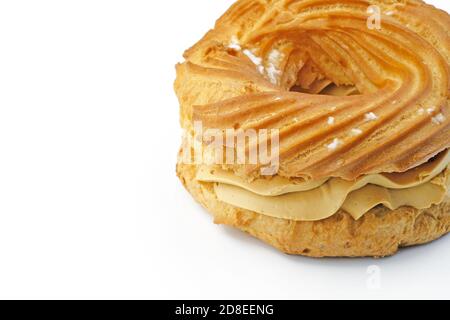 Eclair with butter cream on a white background. Round quiche with cream close-up. Dessert stuffed with condensed milk. Stock Photo