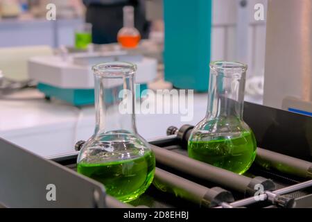 Orbital shaker for mixing, shaking, blending biological samples in glass vials at pharmacy factory, medical exhibition: close up. Chemistry Stock Photo