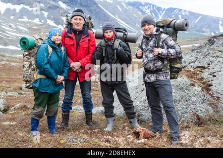 Group of Caucasian hikers with backpacks, senior couple with young and adult men, happy mountaineers portrait Stock Photo
