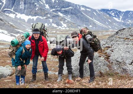 Group of tired climbers stand shoulder to shoulder, portrait from senior couple, teenage boy and adult man, people dressing mountaineering outfit Stock Photo