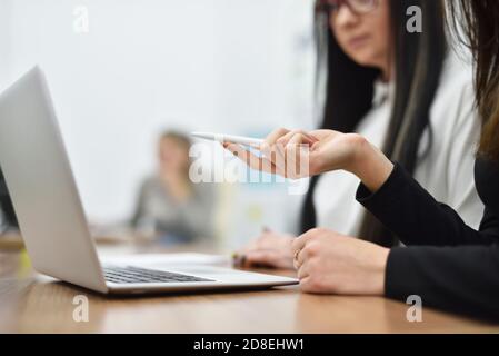 Two young female managers are working on a new project using a laptop Stock Photo