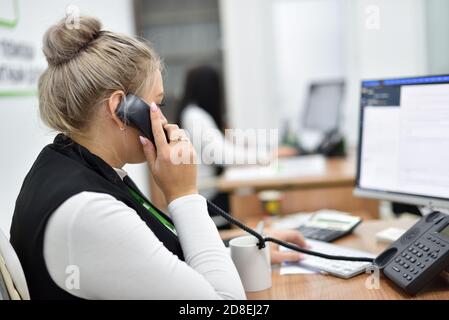 A woman works in the call center and talks on the phone with customers Stock Photo