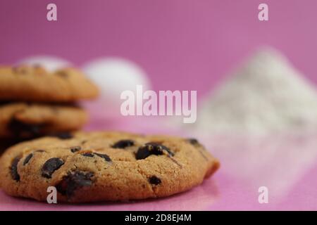 kitchen cooking process homemade chocolate cookies with chocolate drops in the background flour and chicken eggs lie on a pink fuchsia mirror backgrou Stock Photo