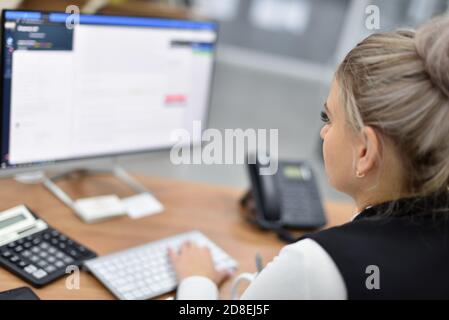 A woman works in an office and looks at the monitor Stock Photo