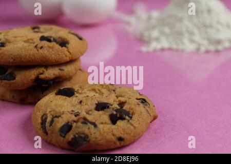 kitchen cooking process homemade chocolate cookies with chocolate drops in the background flour and chicken eggs lie on a pink fuchsia mirror backgrou Stock Photo