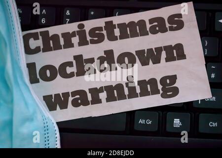 Close-up of Christmas Lockdown Warning Newsprint on a computer keyboard with face covering on right hand side Stock Photo
