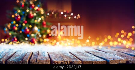 Abstract Christmas - Snowy Table With Bokeh Lights And Defocused Christmas Tree Stock Photo