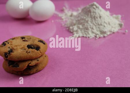 kitchen cooking process homemade chocolate cookies with chocolate drops in the background flour and chicken eggs lie on a pink fuchsia mirror backgrou Stock Photo