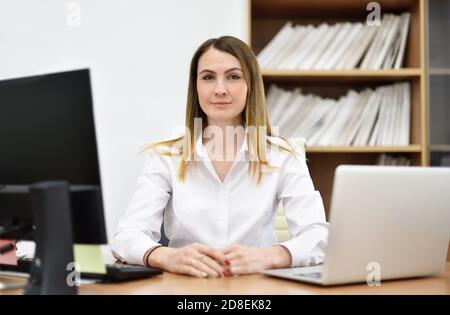 Portrait of middle aged woman office manager at her desk in office Stock Photo