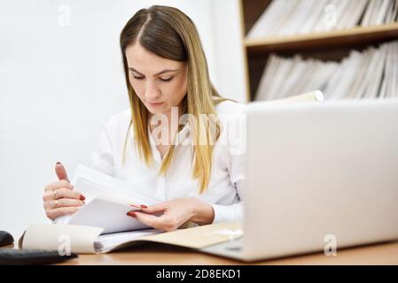 Middle aged woman office manager looking for office documents in the office Stock Photo