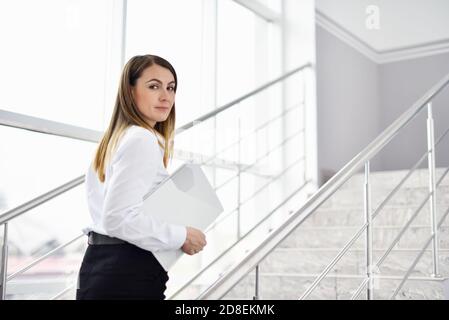 Middle aged woman walking the stairs and carrying a resume to get a job Stock Photo