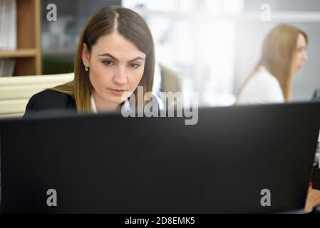 Concentrated middle aged woman working on her desktop computer in a modern office Stock Photo